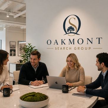 Four colleagues in a modern office discussing work around a table with Oakmont Search Group logo.