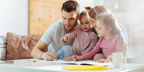 Padre e hijos dibujando juntos en una mesa.