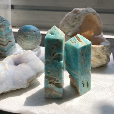 Hemimorphite and raw blue lace agate with quartz geode on a table