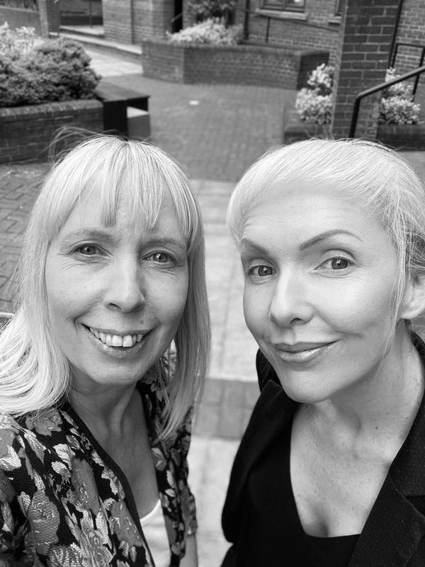 Two women stood side by side, smiling to camera.