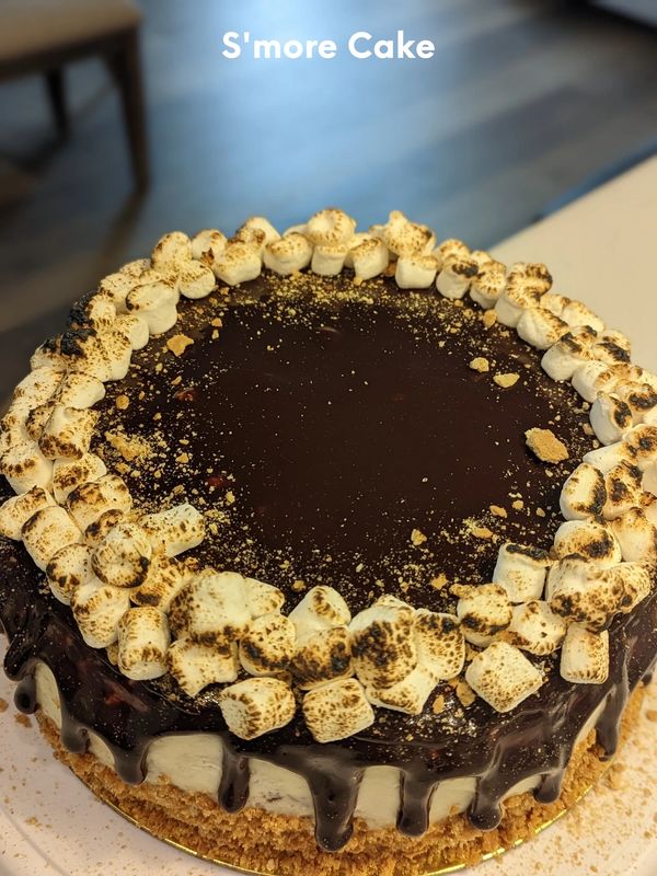 Toasted marshmallow with ganache flowing over the side of the cake. S'mores cake