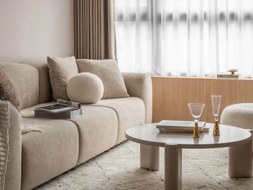 Cozy beige living room with a modern sofa and round coffee table.