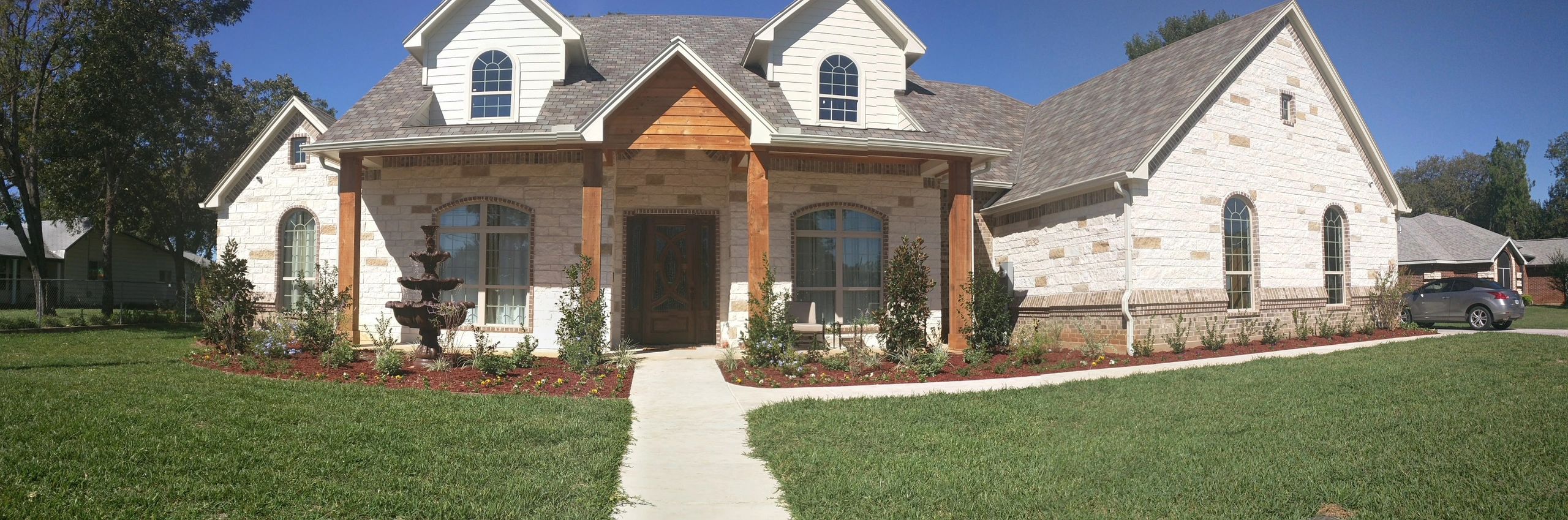 Spacious stone house with wooden accents and well-kept garden.