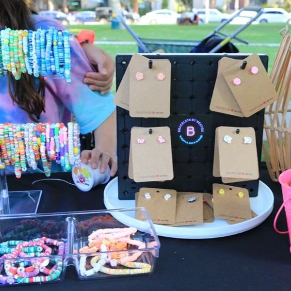 Colorful handmade bracelets and earrings displayed at an outdoor market stall.