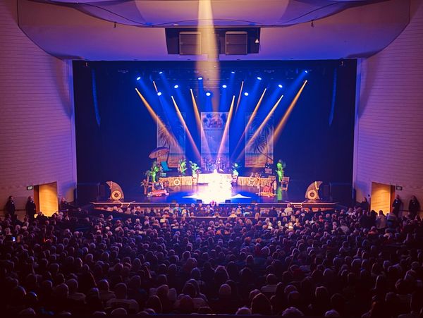 A packed theater with a brightly lit stage and colorful decorations.
