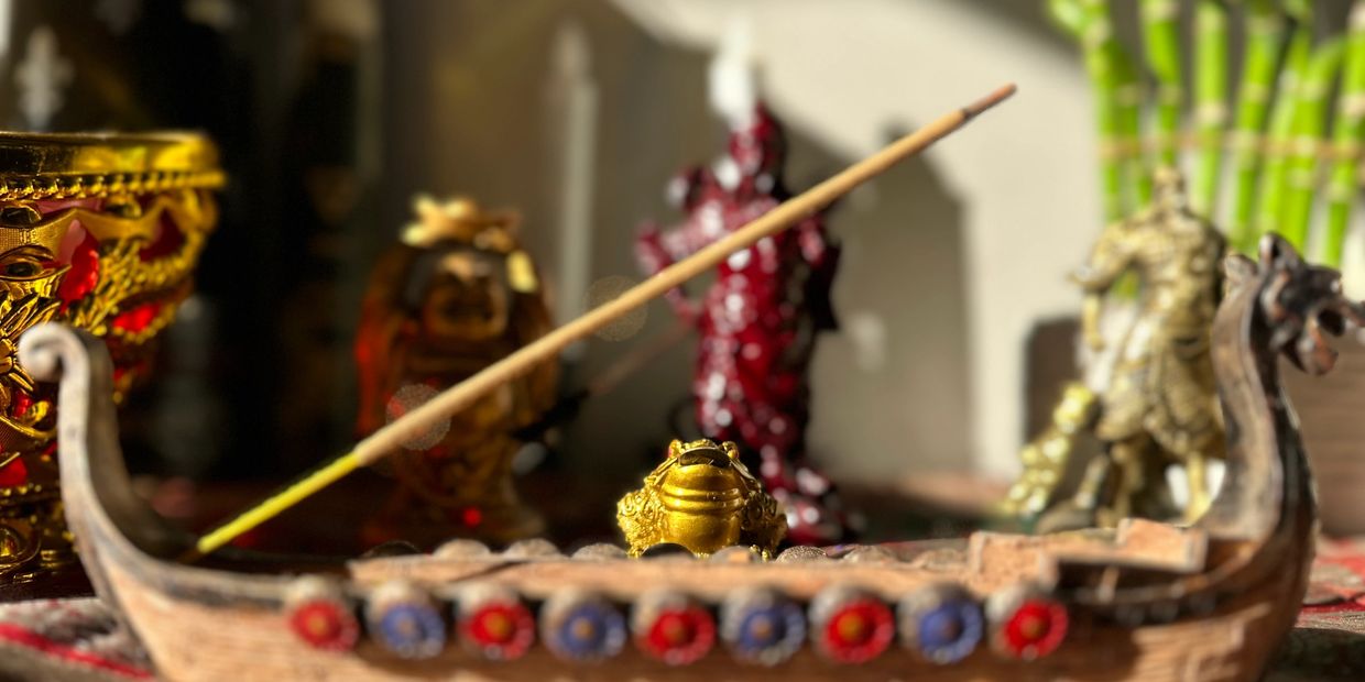 Golden frog incense holder with miniature statuettes in background.