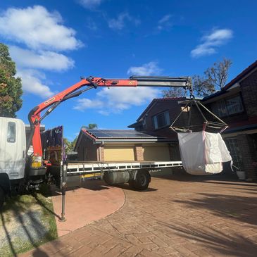 A bulk bag of landscape product being unloaded. 