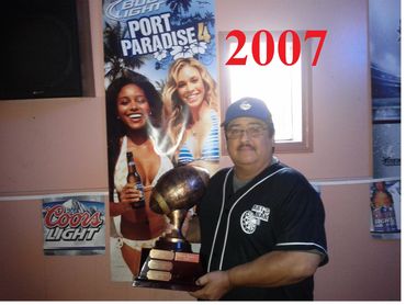Man holding a trophy in front of promotional posters in 2007.