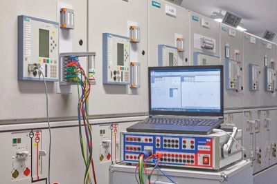Laptop connected to control panels in an industrial setting.