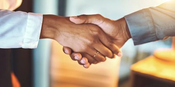 Two people shaking hands in a business setting.
