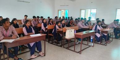 Students attentively listening in a classroom with natural light from windows.