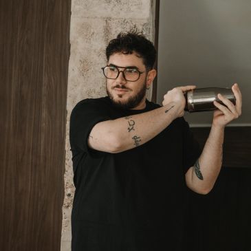 A man shaking a cocktail shaker with focus and style.