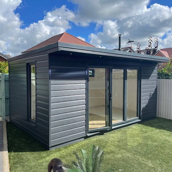 Modern backyard garden room with glass doors and dark siding.