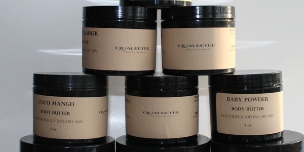 Stacked jars of body butter with natural labels in various scents.