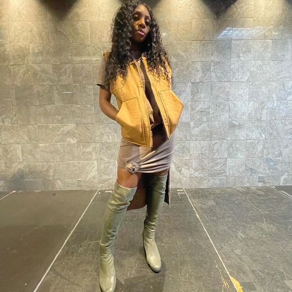 Woman striking a pose in a brown outfit with over-the-knee boots.