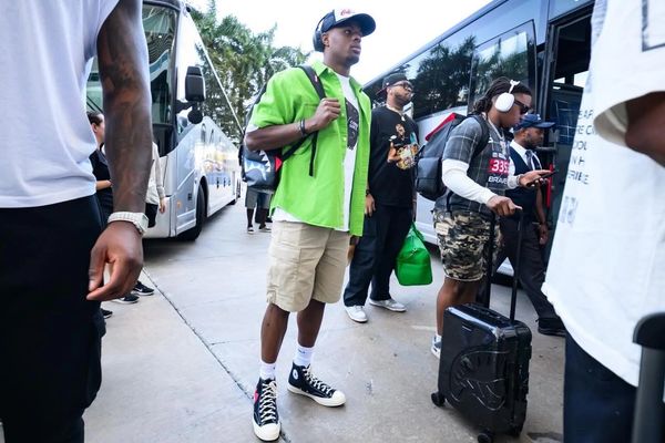 Young men with luggage boarding a bus outdoors.