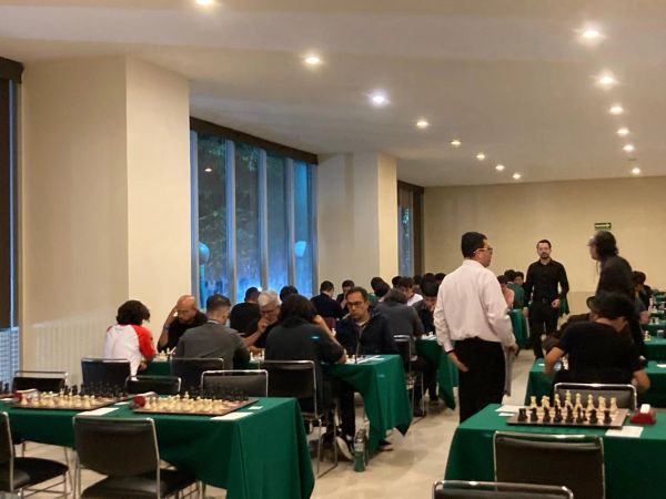 Personas jugando ajedrez en un salón.