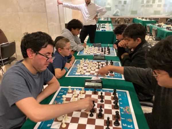 Varias personas jugando ajedrez en una competición.