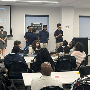Students presenting in a classroom while others listen attentively.