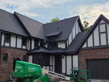 Freshly painted Tudor-style house with brick and stucco exterior under cloudy sky.