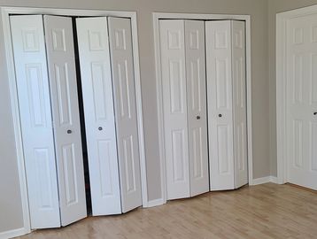 Empty room with white bi-fold closet doors and hardwood floor.