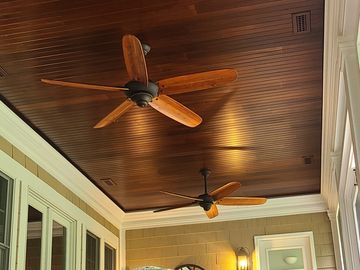 Cozy outdoor seating area with wooden ceiling fans and wicker furniture.