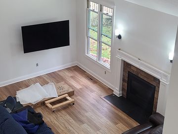 Modern living room with wooden floor, leather sofas, mounted TV, and fireplace.