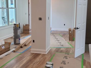 Interior of a house under renovation with protective floor covering and paint supplies.