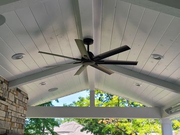 Ceiling fan with seven blades on a white wooden porch ceiling.