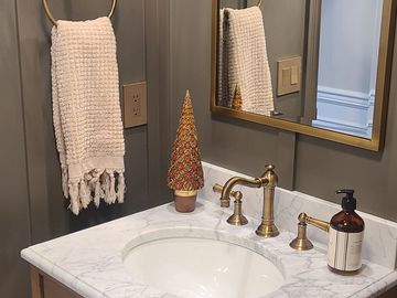 Elegant bathroom vanity with brass fixtures and a festive greenery wreath.