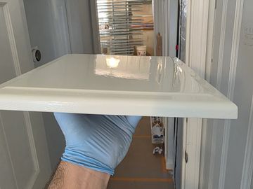 Hand holding a freshly painted glossy cabinet drawer.