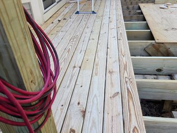 Partially constructed wooden deck with tools and coiled red cable.