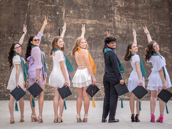 A group of happy graduates posing with their caps and making peace signs.