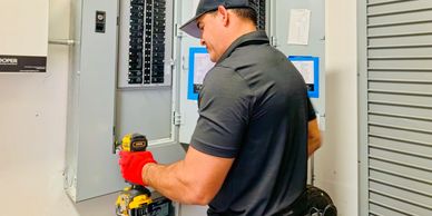 Electrician working on a control panel with tools.