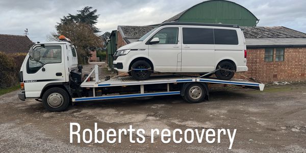 Silver pickup truck on a white flatbed tow truck in a parking area in Warwick.