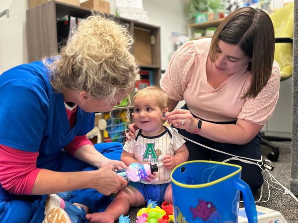 Audiologists testing a young child.