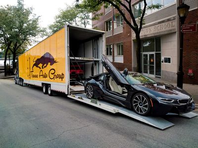 Car hauler with enclosed trailer loading an expensive car BMW i8