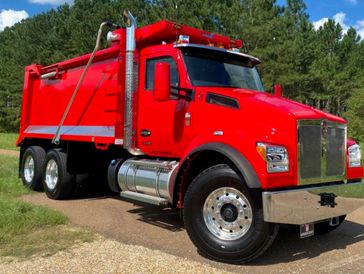 Bright red heavy-duty dump truck parked on a rural road.