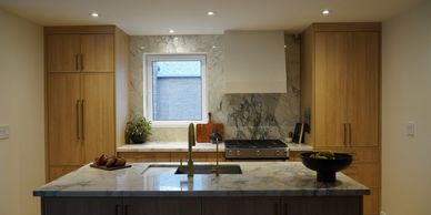 Modern kitchen with marble countertops and wooden cabinets.