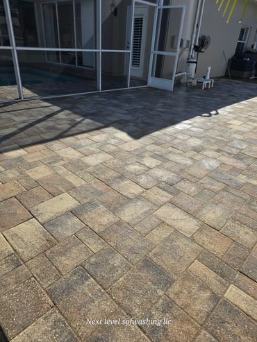 Clean outdoor patio with stone tiles and open door to a screened area.