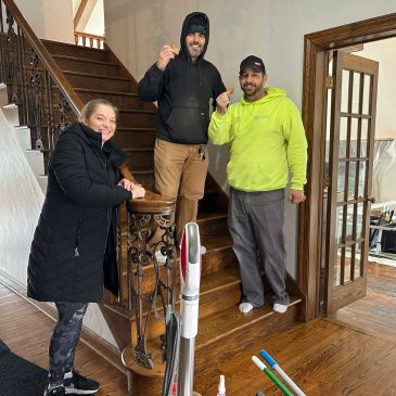 Three people standing on and near stairs, smiling.