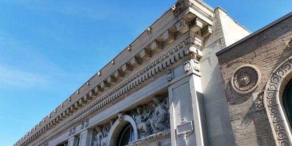 Ornate building facade with sculptures under blue sky.