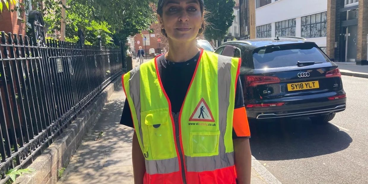 photo of a V I safety Volunteer wearing a high Vis vest standing in the street