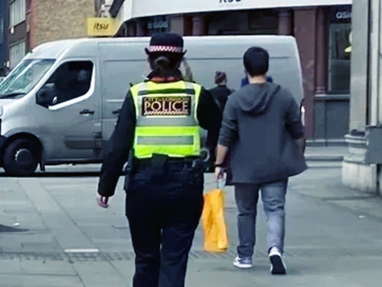 V I Safety logo and photo of the back of a police officer walking down a busy street