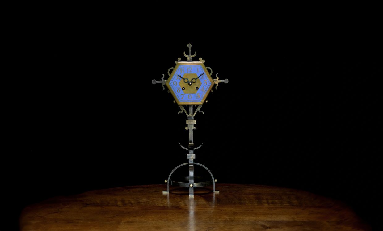 Intricately designed hexagonal clock with blue face on wooden table.