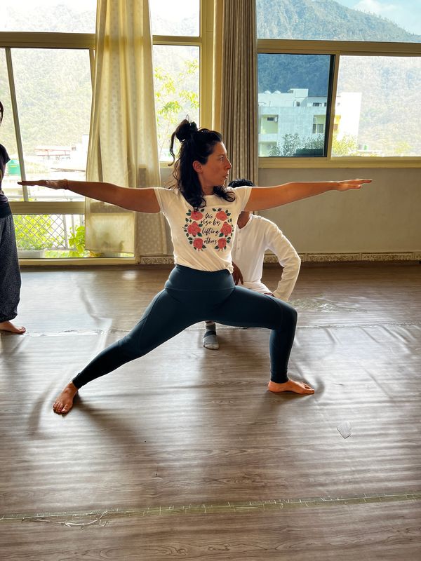 Femme en position de yoga dans une salle lumineuse.