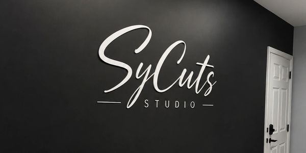 Logo of SyCuts Studio on a black wall.