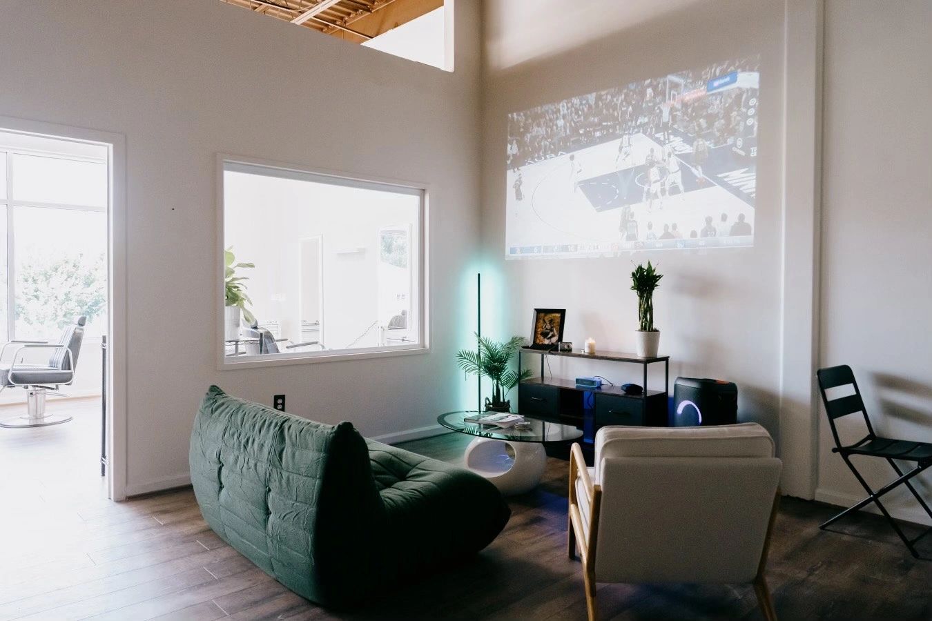 Modern living room with projector showing basketball game on wall.