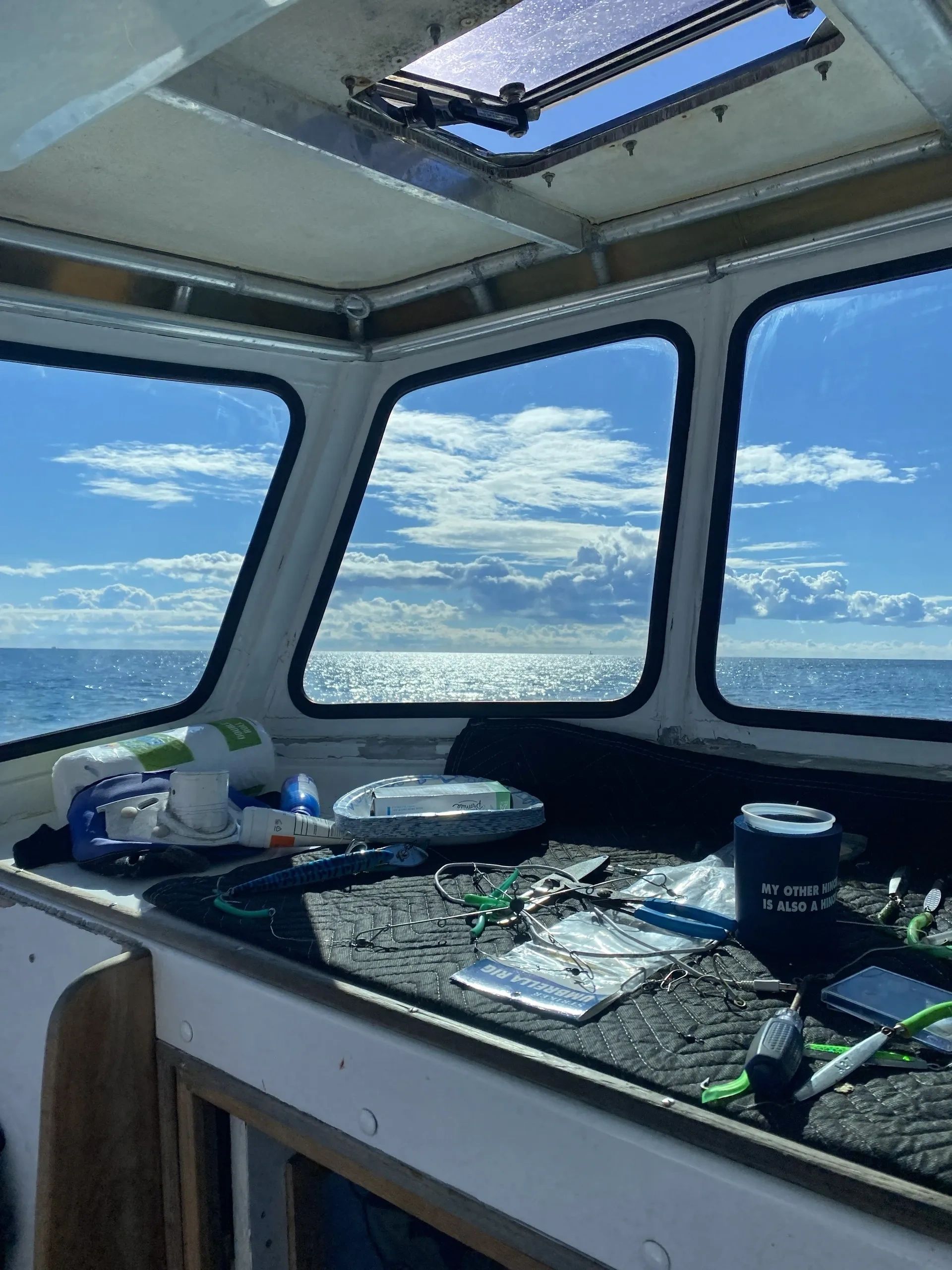 View from a boat cabin with fishing gear and ocean scenery.