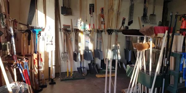 A store corner with various garden tools hanging and standing.